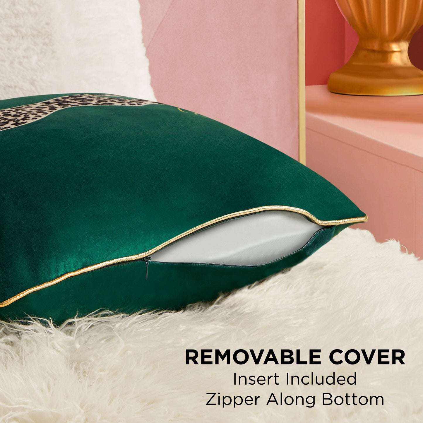 The Velvet Cheetah Square Pillow, featuring a green removable cover with cheetah applique and a white insert, is shown partially unzipped on a fluffy white surface near a gold lamp and pink Juicy Couture furniture. Text: Removable cover. Insert included. Zipper bottom.