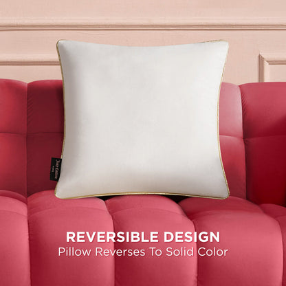 The Velvet Cheetah Pillow with gold piping rests on a red tufted sofa. A black side tag is visible. Text below reads: Reversible Design—this decorative pillow reverses to a solid color.