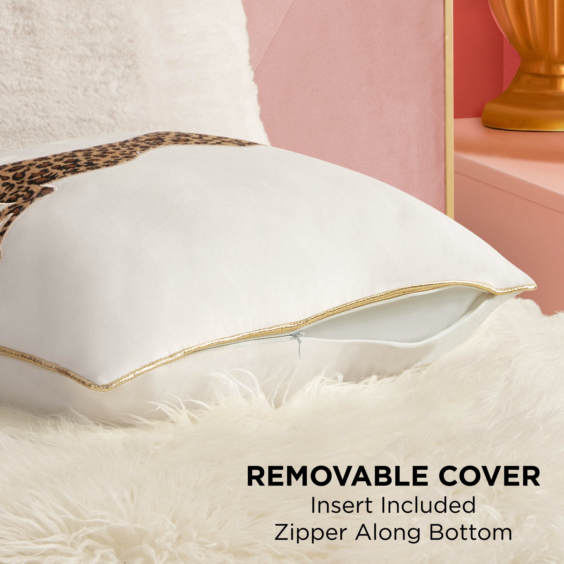 The Velvet Cheetah Pillow features a luxe leopard print, gold trim, and a removable cover with a zipper along the bottom; insert included. Shown resting on a fluffy white surface with the zipper partially open to display the insert inside.