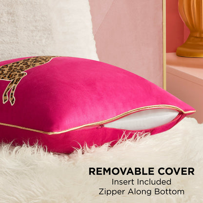 A vibrant pink Velvet Cheetah Square Pillow with gold piping and a leopard print sits on a white fur surface. Its cover is partially unzipped at the bottom, showing the insert. Text: REMOVABLE COVER, Insert Included, Zipper Along Bottom.