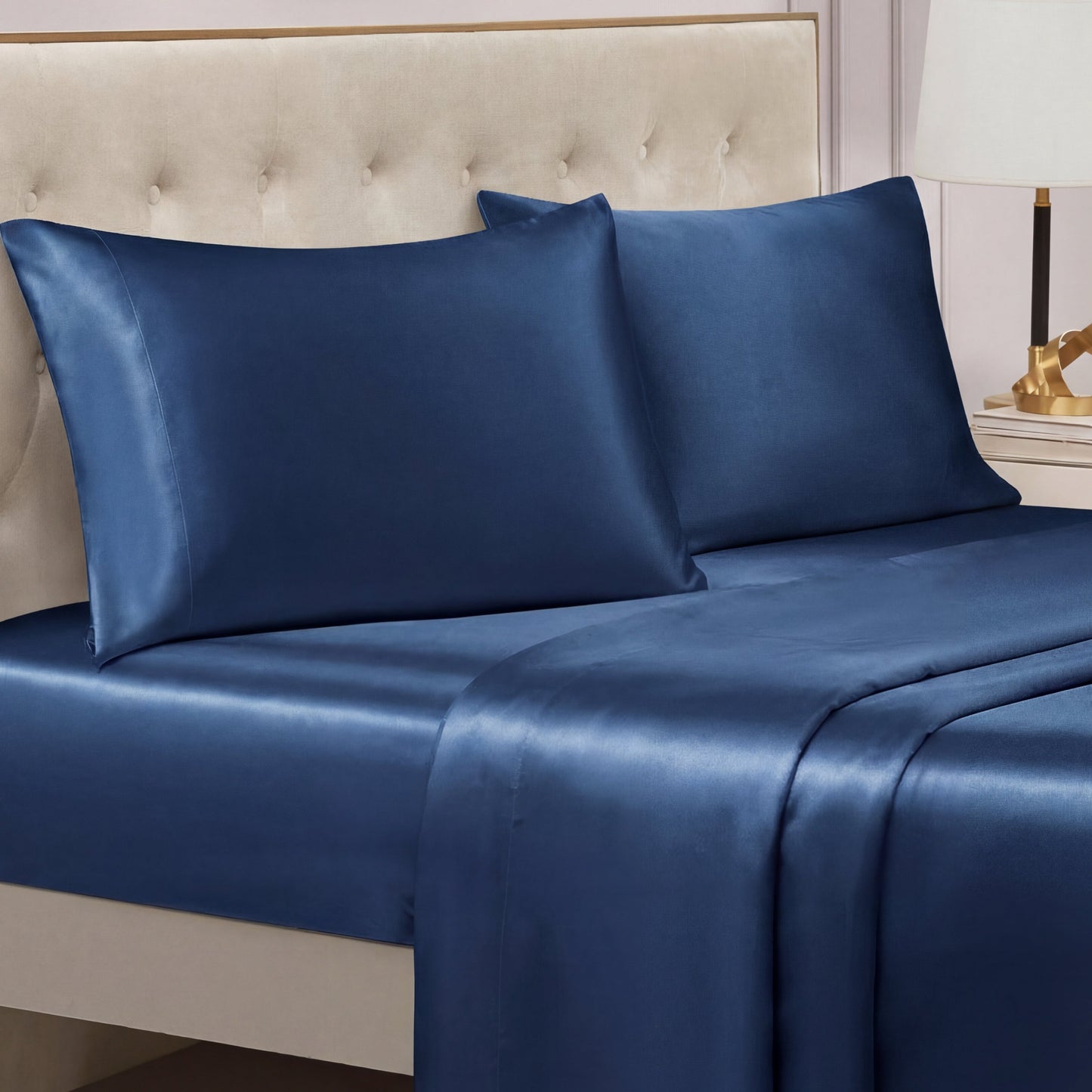 A neatly made bed features the Solid Satin Sheet Set with matching pillowcases and a light beige upholstered headboard in a modern bedroom—ideal for those seeking luxurious satin bedding.