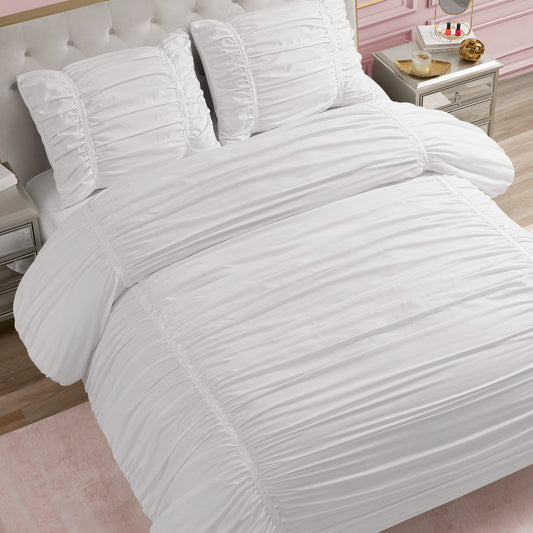 A neatly made bed features the Ribbon Ruched Comforter Set with matching pillows, set in a bedroom with light wood floors, a pink accent rug, and nightstands. Subtle ribbon ruching adds an elegant touch to the cozy space.