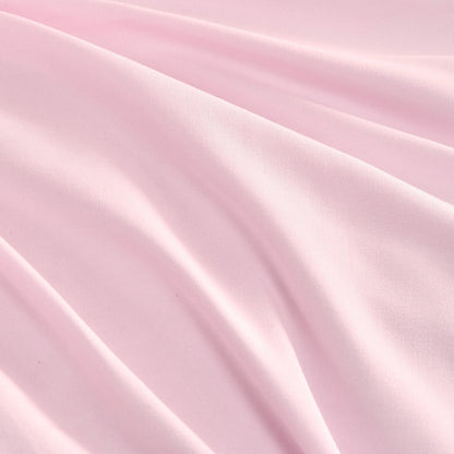 The Ribbon Ruched Comforter Set features soft pink fabric with gentle folds and a smooth texture, creating subtle shadows and highlights that evoke the luxurious feel of a Juicy Couture comforter set.