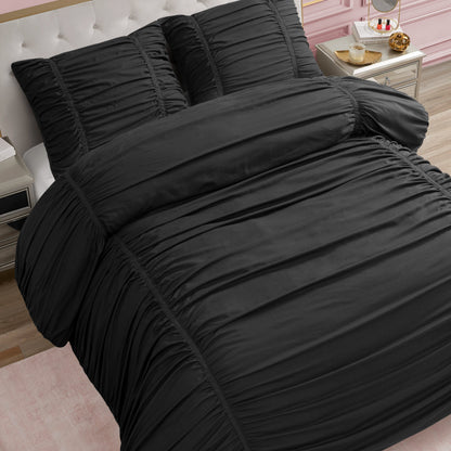 A neatly made bed features the Ribbon Ruched Comforter Set in black with matching pillows, set in a stylish bedroom with a white tufted headboard, pink wall, gold nightstand, and light wood floor.