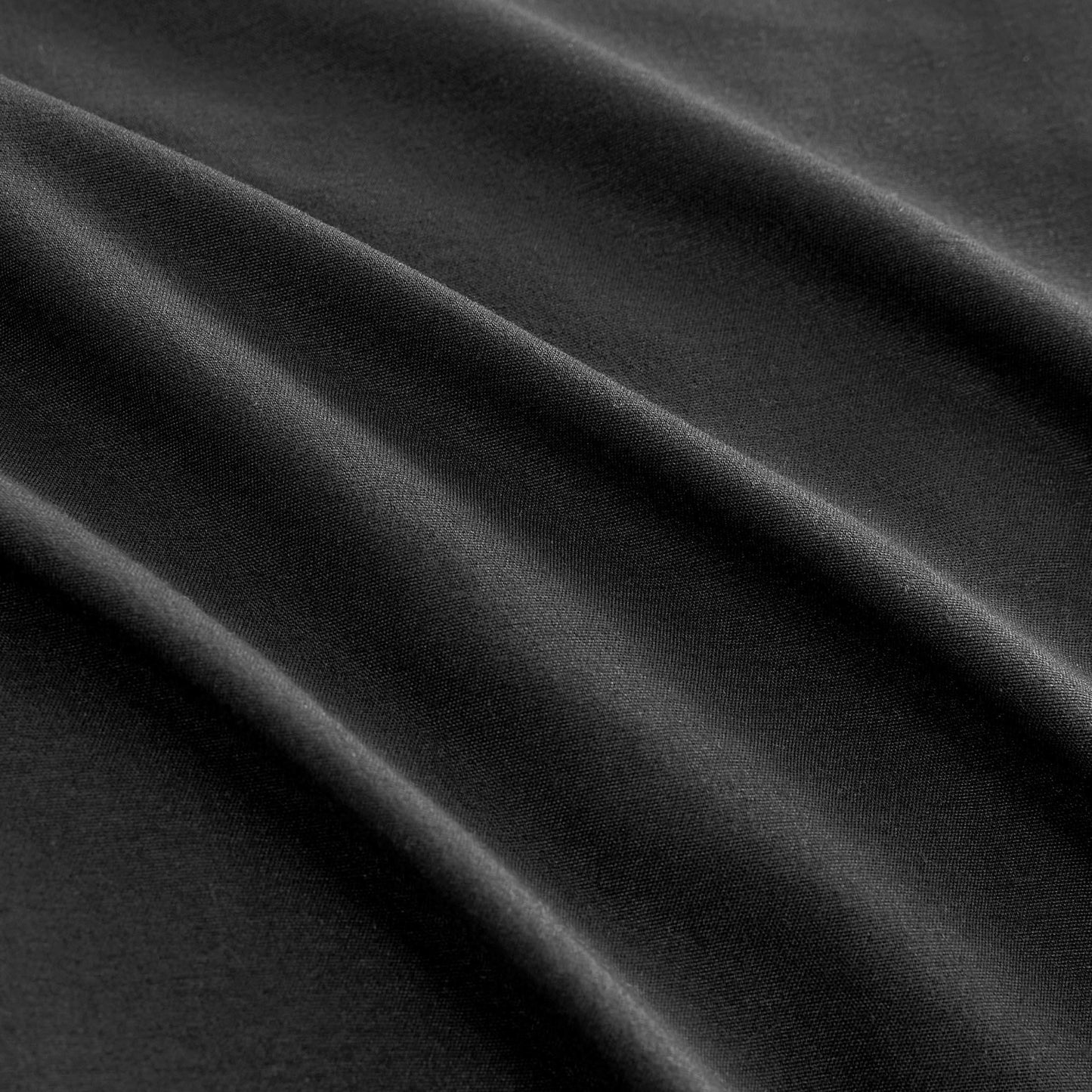 Close-up of smooth black fabric with gentle, diagonal folds and soft shadows, highlighting the texture and drape of the Ribbon Ruched Comforter Set.