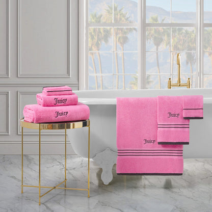 A luxurious bathroom with a white bathtub, gold faucet, and plush Neon Border Bath Towel Set folded on a gold side table and hanging on the tub. Large windows reveal palm trees and mountains outside.