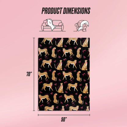 A 70x50 inch ultra-soft Plush Throw Blanket by Juicy Couture features a cheetah and pink bow pattern on black. The image shows the throw draped over a couch and person, with "Product Dimensions" text above.