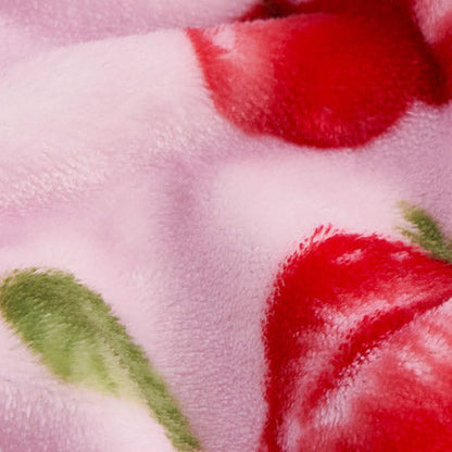 Close-up of the Plush Throw Blanket in soft, fuzzy pink fabric with red and green floral patterns, highlighting its smooth texture and vibrant colors.