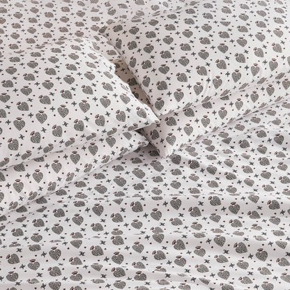Close-up of a bed with white sheets and pillowcases featuring a small, dark floral and geometric pattern. The Microfiber Sheet Set With Extra Pillowcases offers luxury bedding that looks soft, neat, and elegantly arranged.