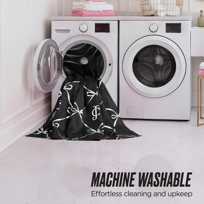 A black and white patterned Shower Curtain and Hooks Set is partially inside an open front-loading washer in a modern laundry room. Text reads: MACHINE WASHABLE. Easy to clean for stylish, low-maintenance bathroom decor.