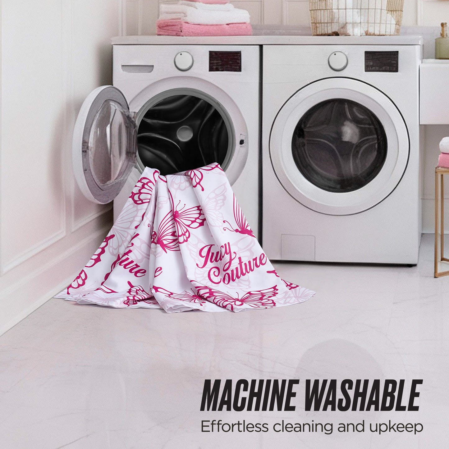 A white and pink shower curtain from the Juicy Couture Shower Curtain and Hooks Set hangs partly in and out of a front-loading washer, next to a dryer. Text: MACHINE WASHABLE—Effortless cleaning, just like your favorite Juicy Couture set.