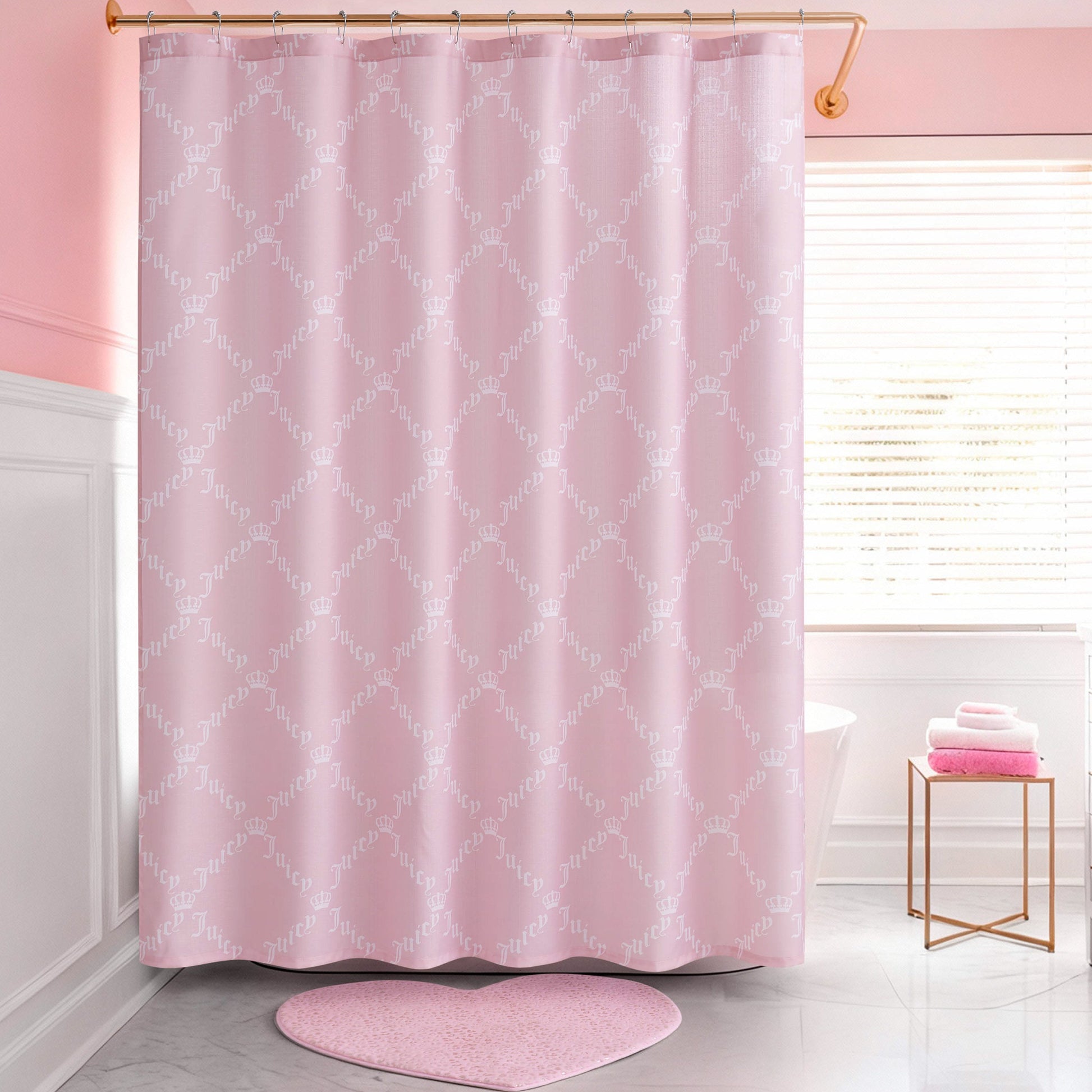 A pink bathroom with a Shower Curtain and Hooks Set featuring a subtle white pattern, a pink heart-shaped bath mat, a white tub, neatly folded pink and white towels on a gold stand, and large windows letting in natural light.