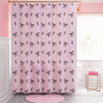 The PEVA Shower Curtain Liner features a pink design with black bows and cursive letters, hanging in a chic pink and white bathroom with a window, pink towels, and a coordinating rug. This waterproof liner adds stylish flair to your space.