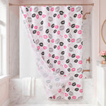 The Cheetah Kisses Shower Curtain with PEVA Liner and Hooks 14-Piece Set makes a bold statement in this marble bathroom, featuring a white background decorated with playful pink and black lipstick kiss prints and chic animal patterns. A neatly folded white towel rests on the tub, enhancing the stylish decor, while a small vase of pink flowers adds a cheerful touch to the window ledge.