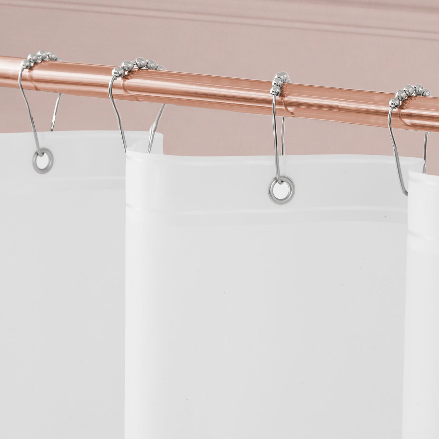 Close-up of the Cheetah Kisses Shower Curtain with PEVA Liner and Hooks 14-Piece Set displayed on a copper curtain rod with silver hooks. The bold white shower curtain stands out against a pale pink wall with decorative molding, adding an elegant touch to your bathroom decor.