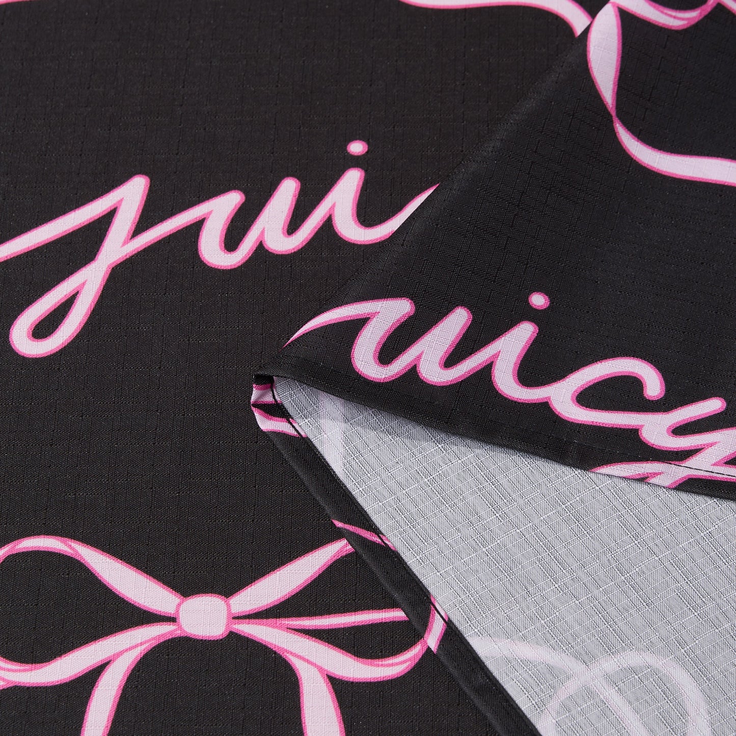 The Sweet Bow Shower Curtain with PEVA Liner and Hooks 14-Piece Set features black fabric adorned with playful pink cursive writing and bow designs, creating a chic statement piece for your bathroom. The curtain is shown folded to highlight both its vibrant front—evoking the classic Juicy Couture shower curtain style—and the lighter, less detailed back, offering versatile inspiration for bath décor.