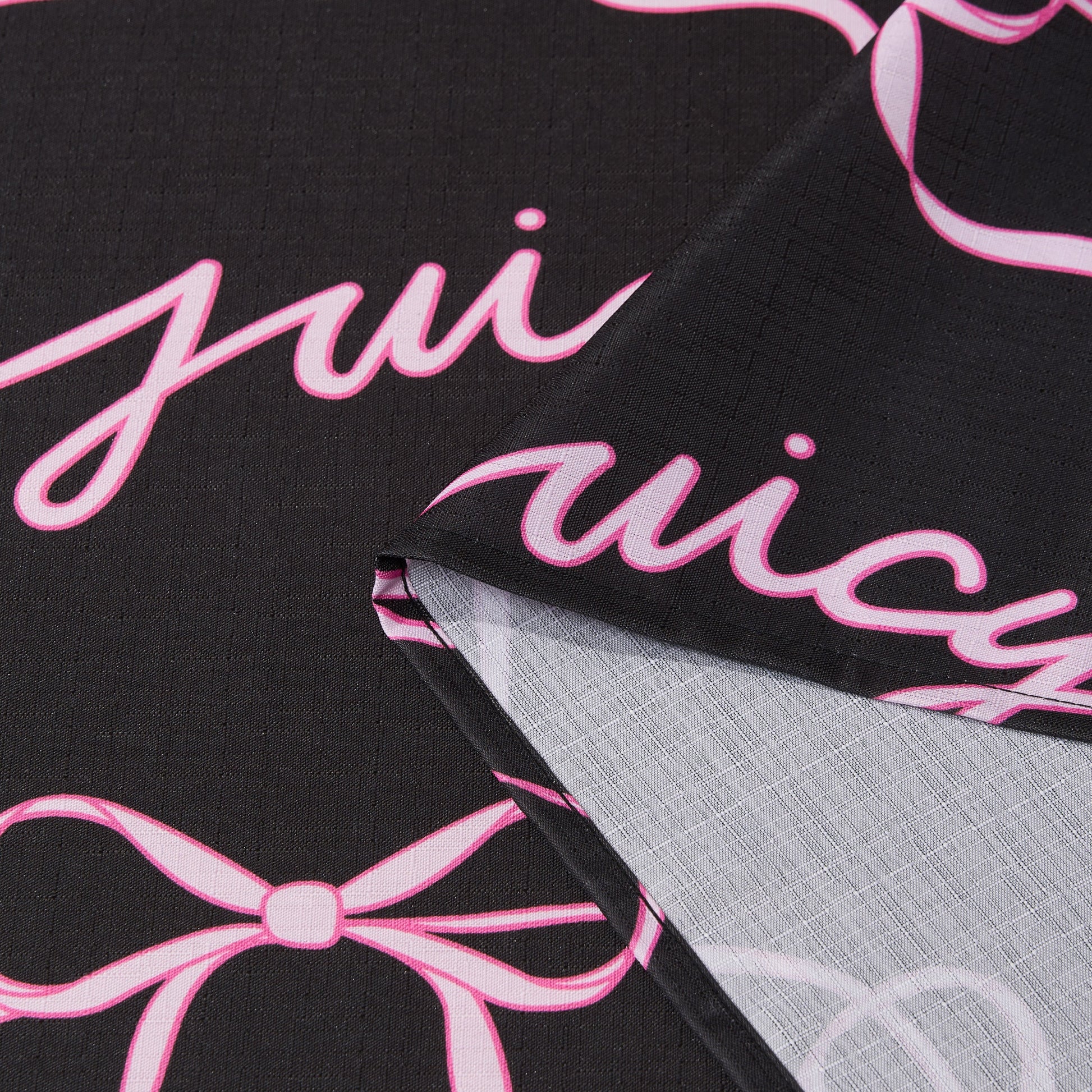 The Sweet Bow Shower Curtain with PEVA Liner and Hooks 14-Piece Set features black fabric adorned with playful pink cursive writing and bow designs, creating a chic statement piece for your bathroom. The curtain is shown folded to highlight both its vibrant front—evoking the classic Juicy Couture shower curtain style—and the lighter, less detailed back, offering versatile inspiration for bath décor.