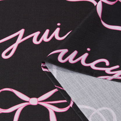 The Sweet Bow Shower Curtain with PEVA Liner and Hooks 14-Piece Set features black fabric adorned with playful pink cursive writing and bow designs, creating a chic statement piece for your bathroom. The curtain is shown folded to highlight both its vibrant front—evoking the classic Juicy Couture shower curtain style—and the lighter, less detailed back, offering versatile inspiration for bath décor.