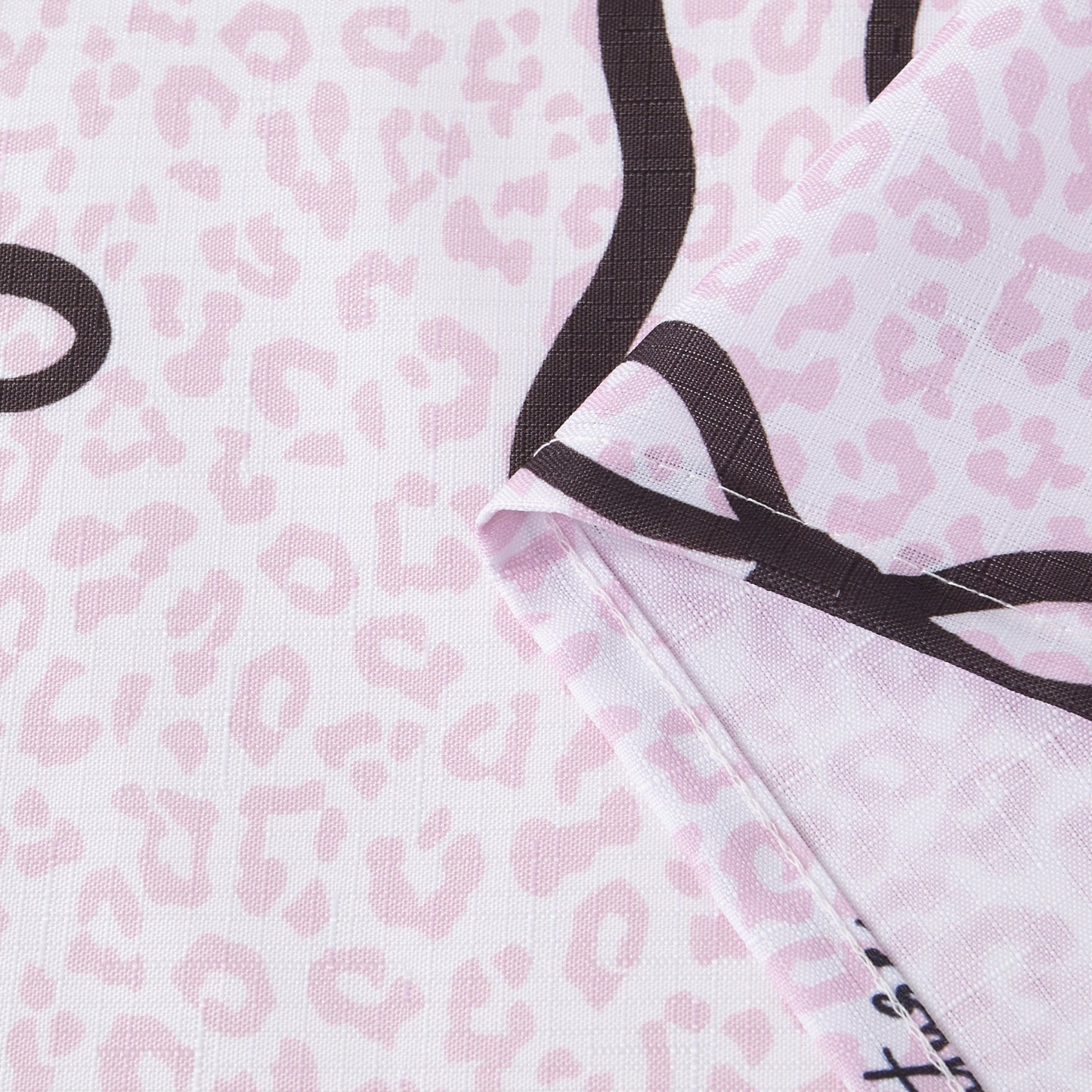 A close-up of the Bow Leopard Shower Curtain with PEVA Liner and Hooks 14-Piece Set showcases its folded fabric featuring a light pink leopard print adorned with bold black curving lines—ideal for bringing a chic, statement-making touch to your bathroom decor.