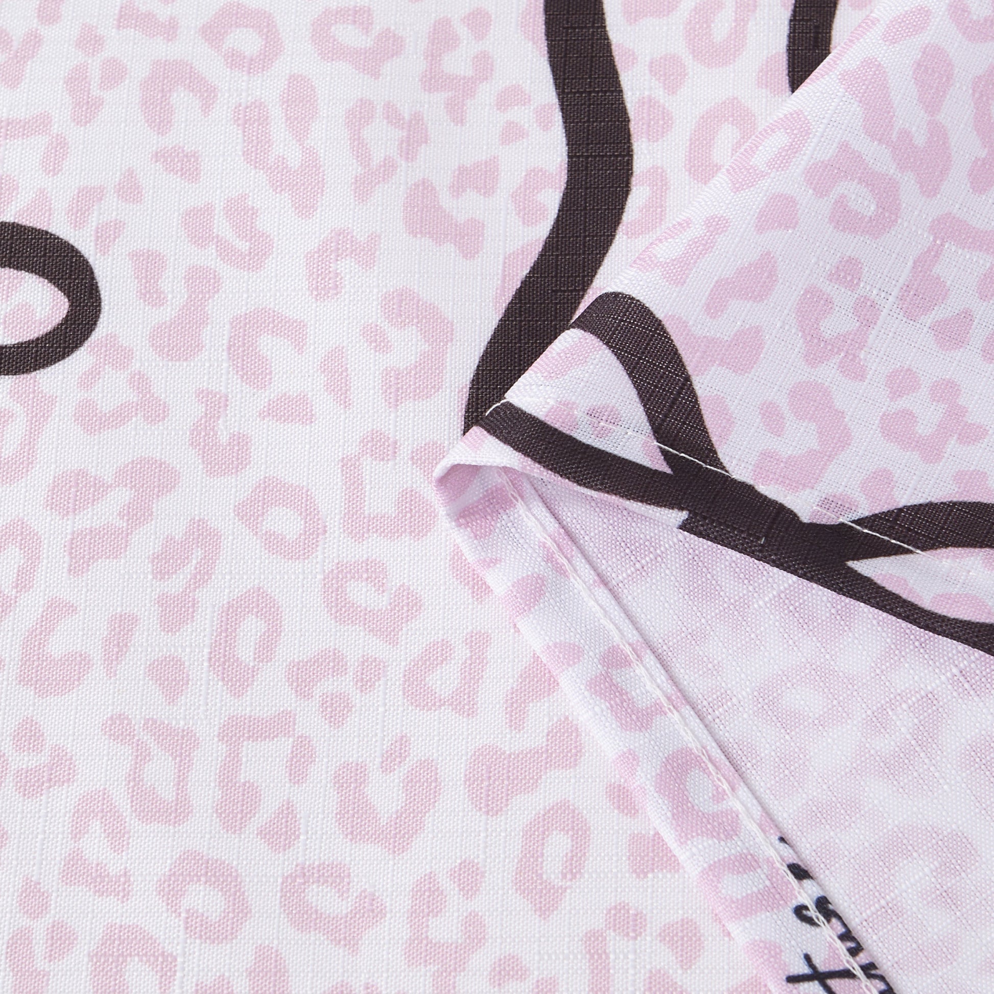 A close-up of the Bow Leopard Shower Curtain with PEVA Liner and Hooks 14-Piece Set showcases its folded fabric featuring a light pink leopard print adorned with bold black curving lines—ideal for bringing a chic, statement-making touch to your bathroom decor.