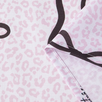 A close-up of the Bow Leopard Shower Curtain with PEVA Liner and Hooks 14-Piece Set showcases its folded fabric featuring a light pink leopard print adorned with bold black curving lines—ideal for bringing a chic, statement-making touch to your bathroom decor.
