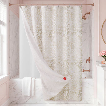 Elevate your bathroom with the Stassi Shower Curtain with PEVA Liner and Hooks 14-Piece Set, featuring an eye-catching white and beige zebra pattern. The statement curtain is partially pulled back to reveal a sleek white tub, while marble walls, neatly folded white towels, and fresh pink roses in a vase add elegant decorative touches.