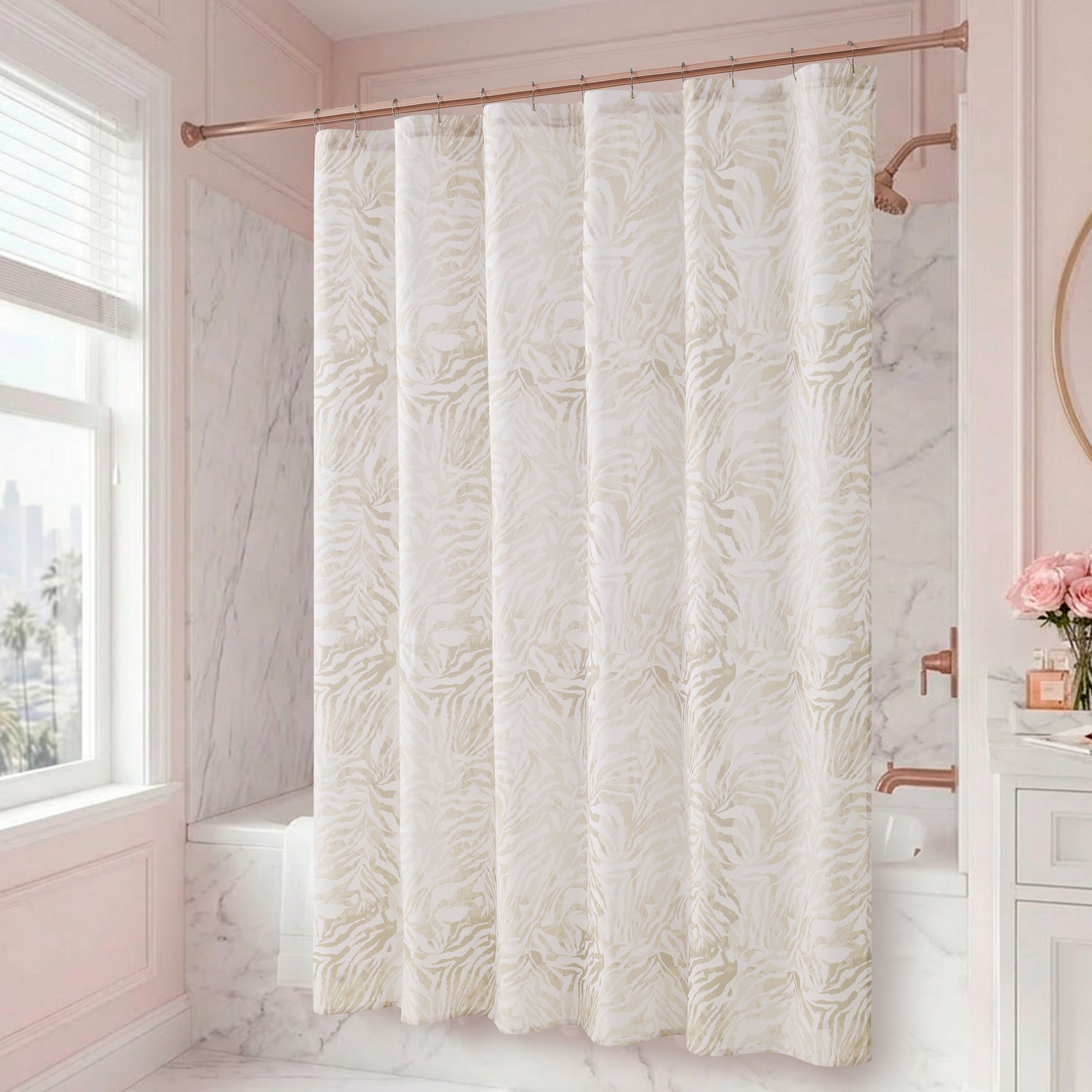 A bathroom with marble walls and a window features the Stassi Shower Curtain with PEVA Liner and Hooks 14-Piece Set in a stylish white and beige pattern, making a striking statement in the space. A vanity adorned with pink flowers in a vase and a round mirror on the right side enhances the elegant bath decor.