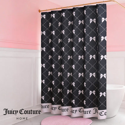A bathroom with white wainscoting and pink walls features the Shower Curtain and Hooks Set, a black fabric curtain with a white bow and lattice pattern, "Juicy Couture" text at the bottom, and the Juicy Couture Home logo in the lower left corner.