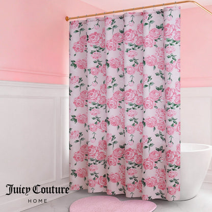 A bathroom with pink walls and white wainscoting features a Shower Curtain and Hooks Set adorned with pink roses. A pink heart-shaped rug adds charm to the decor, with "Juicy Couture Home" written in the bottom left corner of the curtain.