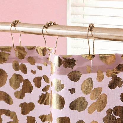 Close-up of the Shower Curtain and Hooks Set featuring a gold and pink leopard print, hanging from a silver rod with metal rings. The background shows stylish bathroom decor, including a pink wall and partially open white blind.