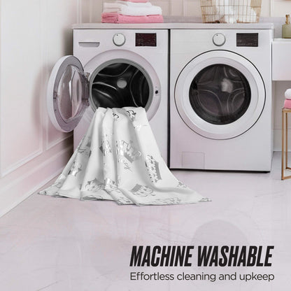 A laundry room features two front-loading machines with a white patterned shower curtain partially inside one washer. Text reads MACHINE WASHABLE: Effortless cleaning and upkeep. Towels and decor are stacked on the machines. Shower Curtain and Hooks Set shown.