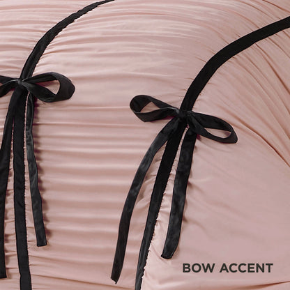 Close-up of pale pink ruched fabric with two velvet bows and black trim from the Amelie Bows Ruched Comforter Set. “BOW ACCENT” appears in the bottom right corner.