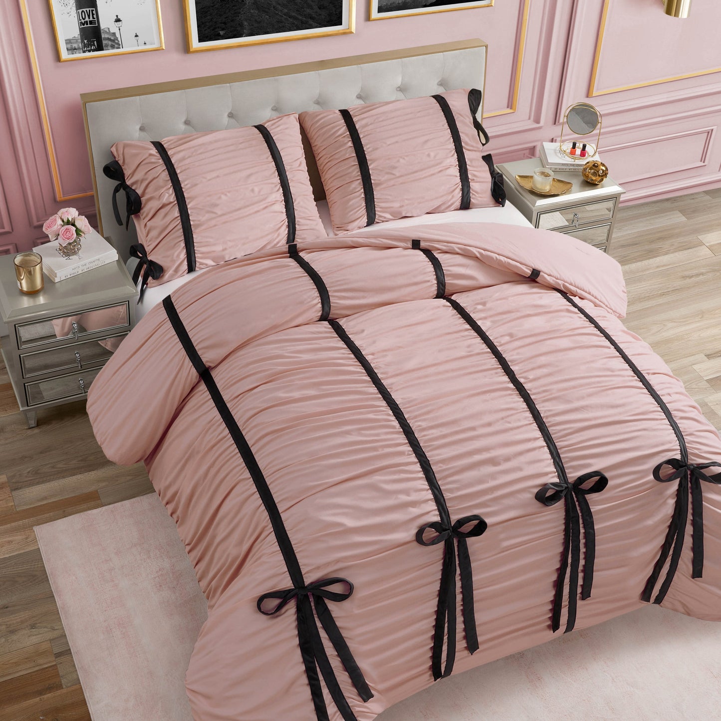A neatly made bed with the ultra-soft Amelie Bows Ruched Comforter Set in pink and pillows featuring black vertical stripes and velvet bows, set in a chic bedroom with pink walls, gold trim, and mirrored nightstands.
