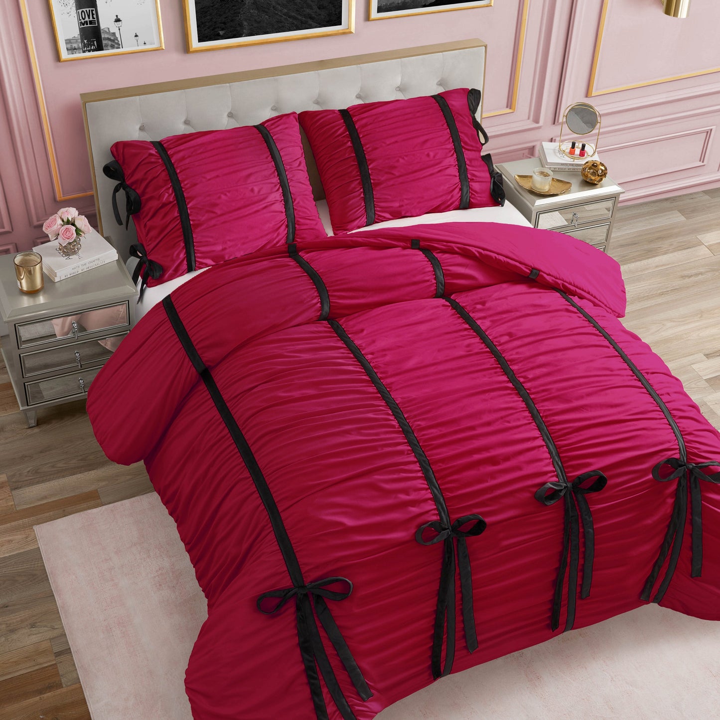 A bed with the Amelie Bows Ruched Comforter Set, featuring bright pink fabric, chic velvet bows, and black stripes, stands in an elegant room with pink paneled walls and modern metallic nightstands.