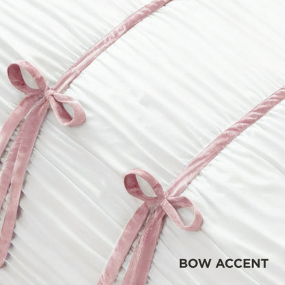 Two pink velvet bows sit atop pleated white fabric with diagonal pink trim, echoing the style of the Amelie Bows Ruched Comforter Set. "BOW ACCENT" is displayed in the bottom right corner.