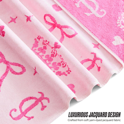 Close-up of the Printed Jacquard Bath Towel Set in pink, featuring crown, bow, and letter motifs in darker pink. “Luxurious Jacquard Design. Crafted from soft yarn-dyed jacquard fabric.” Inspired by Juicy Couture style.