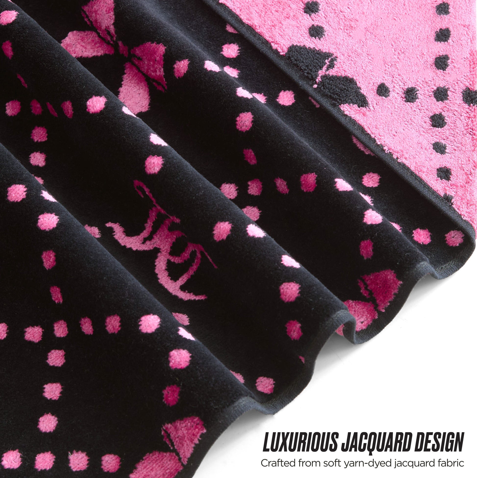 Close-up of a black and pink jacquard fabric with decorative patterns and dots. LUXURIOUS JACQUARD DESIGN—crafted from soft yarn-dyed jacquard for the stylish Printed Jacquard Bath Towel Set collection.