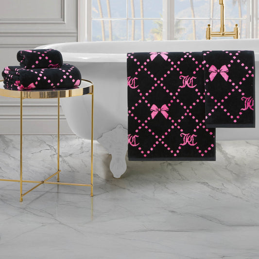 The Printed Jacquard Bath Towel Set, featuring pink bows and dotted diamond patterns, is showcased in a luxurious bathroom with a white bathtub, marble flooring, and a gold side table.