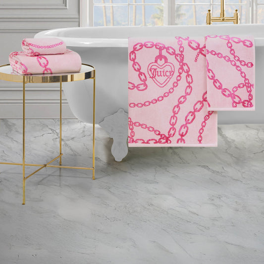 The Printed Jacquard Bath Towel Set, featuring a chain and heart design, drapes over a white claw-foot tub, with additional luxury towels folded on a gold side table beside marble flooring and gold fixtures.
