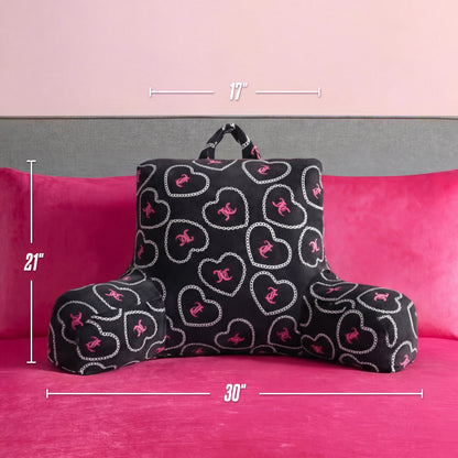 A Juicy Couture Backrest Pillow with pink and white heart and chain designs rests on a hot pink bed; this plush pillow measures 21" tall, 17" wide at the top, and 30" wide at the base.