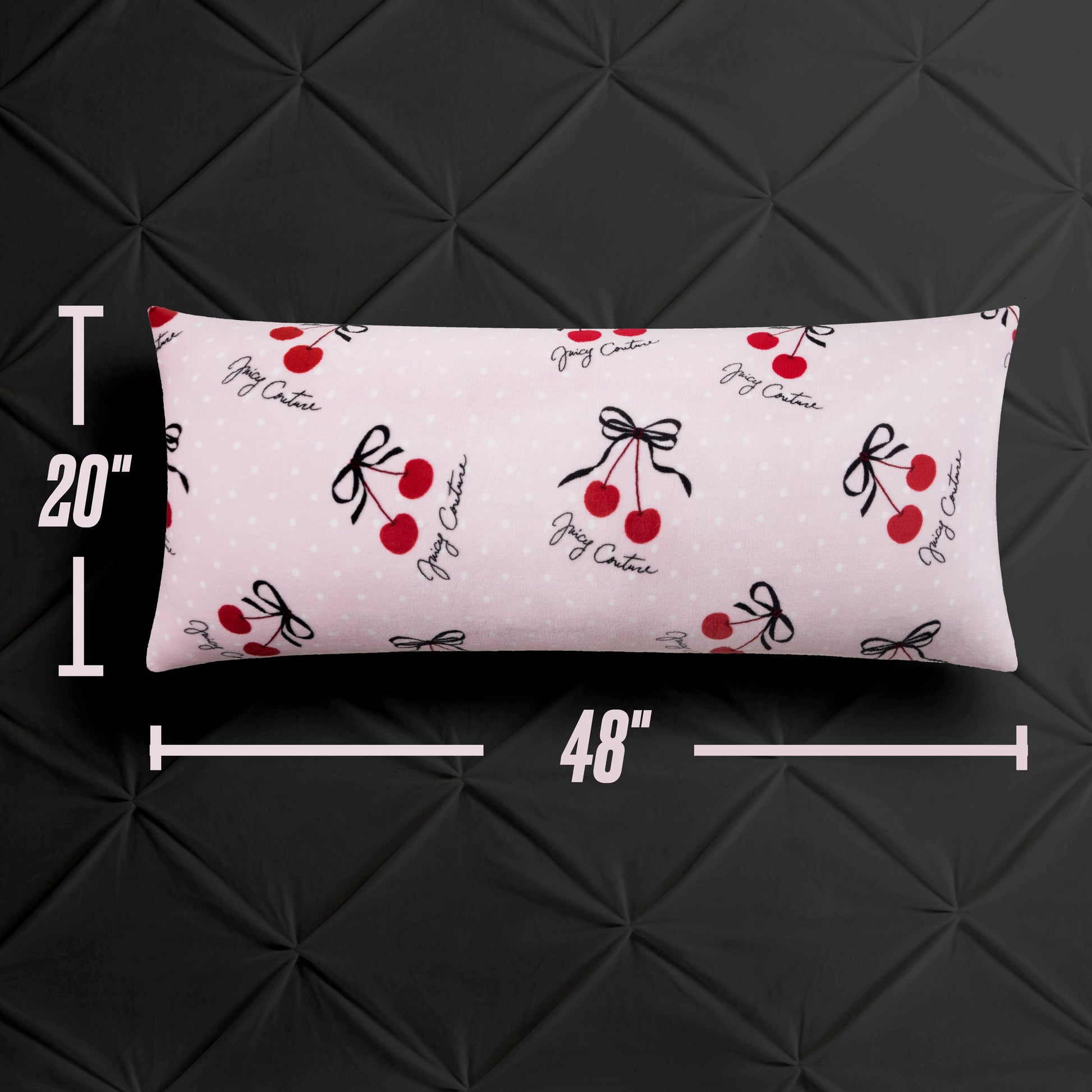 The Plush Body Pillow by Juicy Couture measures 20"x48" and features a chic light pink cover with red cherries, black bows, and "Jigy Chatrie" cursive, displayed against a black quilted background.