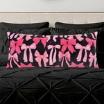 The Plush Body Pillow features an oversized, plush design with various pink bows on a black background, resting on a textured black bedspread with matching pillows.