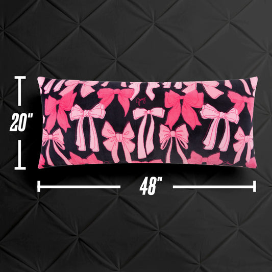 The Plush Body Pillow, featuring a pink bow pattern on black and measuring 20"x48", is shown against a black textured backdrop with measurement markers along the sides.