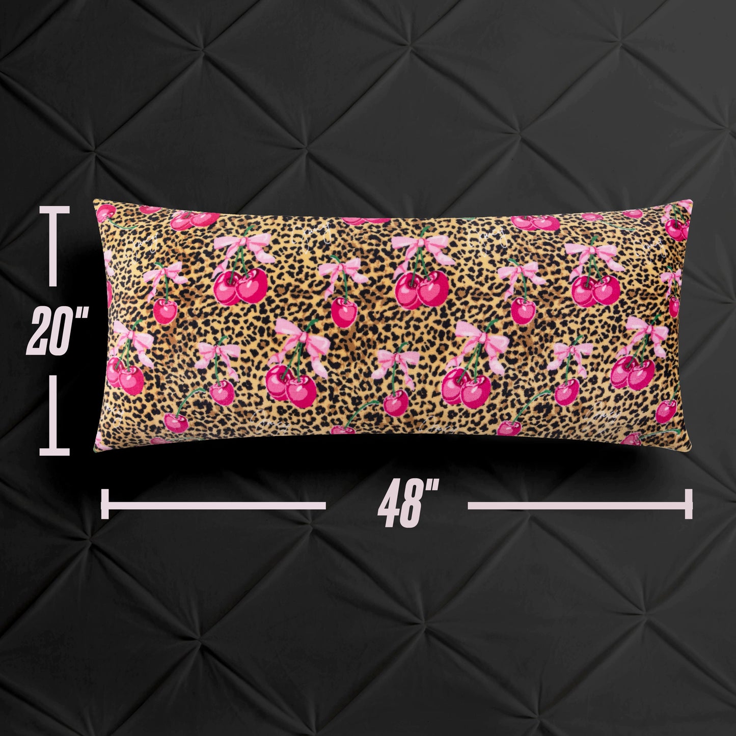 The Plush Body Pillow by Juicy Couture measures 20 x 48 inches, features a soft leopard print with pink cherry accents, and is shown on a black textured surface with measurement lines emphasizing its oversized design.