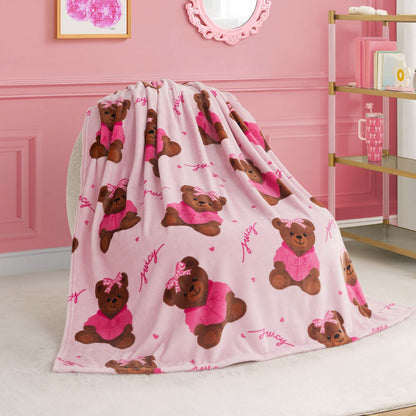 A Kids Plush Throw Blanket in pink, decorated with adorable brown teddy bears in pink outfits and bows, is draped over a chair in a stylish room. This ultra-soft blanket adds cozy charm to shelves, wall art, and mirror accents.