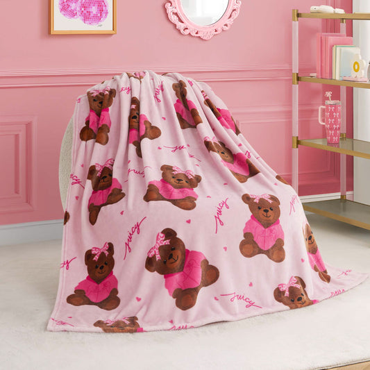 A Kids Plush Throw Blanket in pink, decorated with adorable brown teddy bears in pink outfits and bows, is draped over a chair in a stylish room. This ultra-soft blanket adds cozy charm to shelves, wall art, and mirror accents.