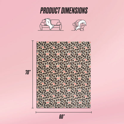 The Plush Oversized Throw Blanket, shown on a pink background, features a leopard and heart print. Measuring 70 x 60 inches, it's perfect for use on a sofa or as a cozy wrap, offering both style and comfort.