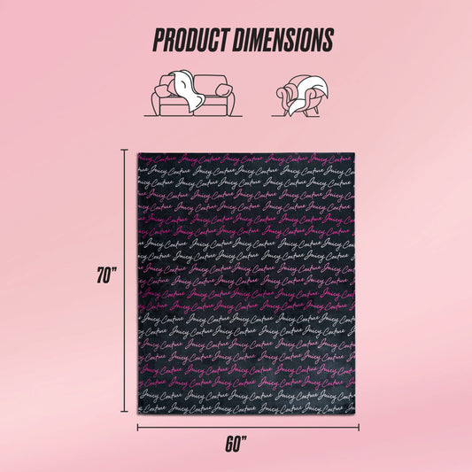 The Plush Oversized Throw Blanket by Juicy Couture, featuring a cursive text pattern, is displayed against a pink background. This ultra-soft rectangular blanket measures 70" x 60" and is ideal for sofas and chairs.