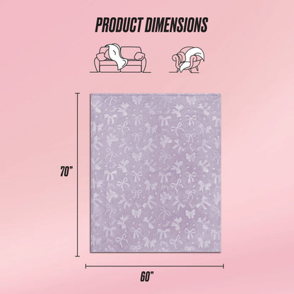 The Embossed Plush Oversized Throw Blanket by Juicy Couture is shown in light purple with a velvety, embossed bow pattern. It measures 70"x60", ideal for sofa or personal use. Icons and "Product Dimensions" appear above on a pink background.