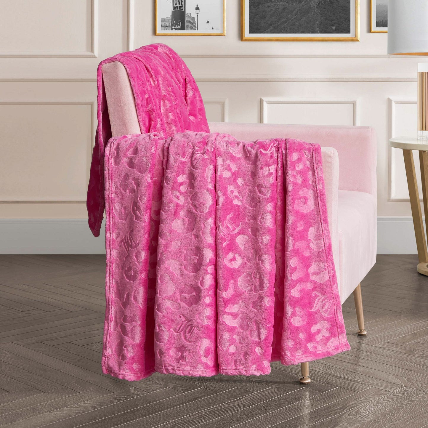 An Embossed Plush Oversized Throw Blanket rests on a pale pink armchair in a modern living room with light paneled walls and framed art.